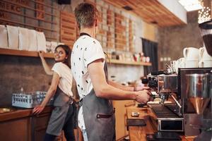 With machine. Two young cafe workers indoors. Conception of business and service photo