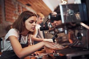 Girl cleans machine. Two young cafe workers indoors. Conception of business and service photo