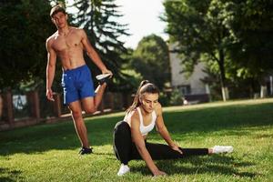 Guys have nice abs. Man and woman have fitness day in the city at daytime in the park photo