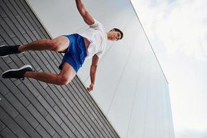 Into the air. Young sports man doing parkour in the city at sunny daytime photo