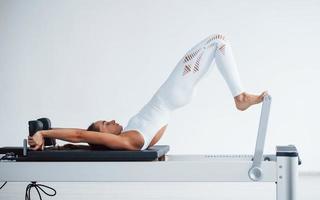 Good for the spine. Confident young sporty woman with slim body type in the healthy center doing exercises by using special equipment photo