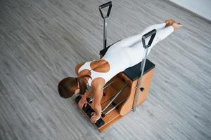 vista aérea. joven deportista segura de sí misma con un tipo de cuerpo delgado en el centro saludable haciendo ejercicios usando equipo especial foto