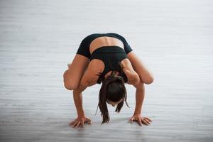 Young sporty woman in black clothes with slim body type in the healthy center doing exercises photo