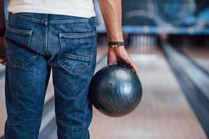 vista de partículas traseras del hombre con ropa informal jugando a los bolos en el club foto