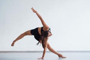 Young sporty woman in black clothes with slim body type in the healthy center doing exercises photo