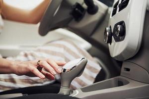 Close up view of woman's hand on gear stick in modern automobile with white interior photo