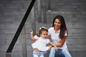 bastante joven madre y su pequeña hija han caminar en la ciudad foto