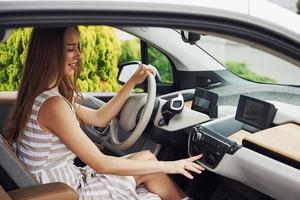 gira la perilla. mujer conductora dentro de un automóvil moderno. probando auto nuevo foto