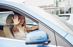 adiós, gesto. mujer conductora dentro de un automóvil moderno. probando auto nuevo foto