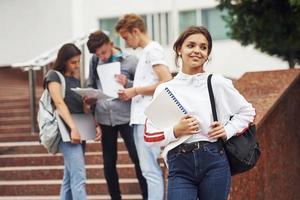 linda chica adolescente. grupo de jóvenes estudiantes con ropa informal cerca de la universidad durante el día foto