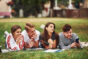 estado de ánimo juguetón. grupo de jóvenes estudiantes con ropa informal sobre hierba verde durante el día foto