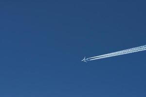 Modern plane flying high in the blue sky at sunny day. Speed and energy photo