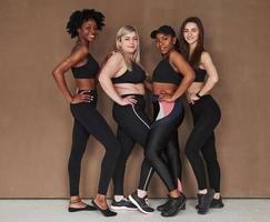 Full lenght photo. Group of multi ethnic women standing in the studio against brown background photo