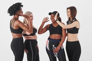 Well done, after workout. Group of multi ethnic women standing in the studio against white background photo