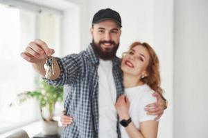 Holds keys. Happy couple together in their new house. Conception of moving photo