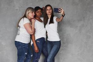 foto horizontal. grupo de mujeres multiétnicas de pie en el estudio con fondo gris