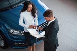 Girl is smiling. Female customer and modern stylish bearded businessman in the automobile saloon photo