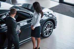 Front part of the car. Female customer and modern stylish bearded businessman in the automobile saloon photo