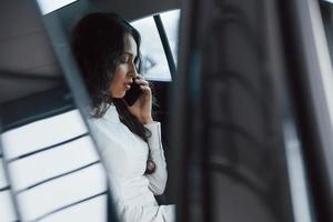 Businesswoman in official wear have call when sitting on the back of car photo