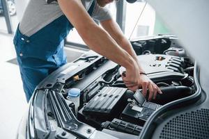 It's harder that it looks. Process of repairing car after accident. Man working with engine under the hood photo