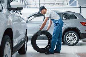 Looks pefect. Mechanic holding a tire at the repair garage. Replacement of winter and summer tires photo