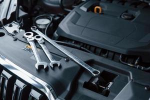 Expensive transport. Repair tools lying down on the engine of automobile under the hood photo