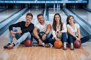 Happy together. Young cheerful friends have fun in bowling club at their weekends photo