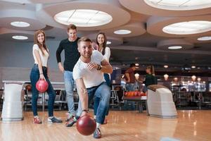 Nice body shape. Young cheerful friends have fun in bowling club at their weekends photo