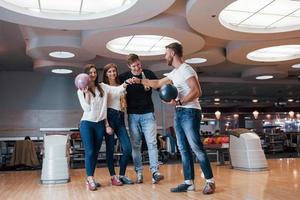 Well done. Young cheerful friends have fun in bowling club at their weekends photo