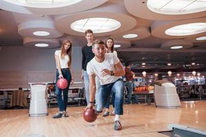 Enjoying the game. Young cheerful friends have fun in bowling club at their weekends photo