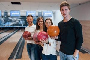 despues del juego. jóvenes amigos alegres se divierten en el club de bolos los fines de semana foto