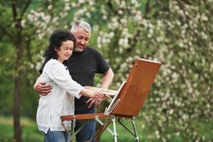 atención a los detalles. pareja madura tiene días libres y trabaja en la pintura juntos en el parque