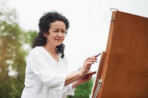 hermosa luz del sol. retrato de pintor maduro con pelo rizado negro en el parque al aire libre foto