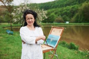Portrait of mature painter with black curly hair in the park outdoors photo