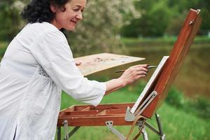 Positive woman. Portrait of mature painter with black curly hair in the park outdoors photo
