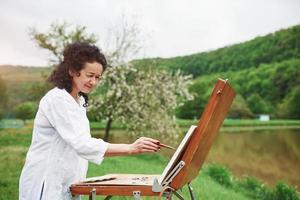 Concentrated at work. Portrait of mature painter with black curly hair in the park outdoors photo