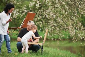 Some new beginnings. Grandmother and grandfather have fun outdoors with granddaughter. Painting conception photo