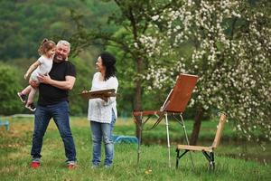 clima cálido perfecto. la abuela y el abuelo se divierten al aire libre con su nieta. concepción de la pintura foto