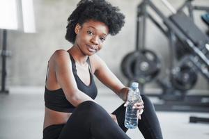 una persona. mujer afroamericana con cabello rizado y ropa deportiva tiene un día de fitness en el gimnasio foto