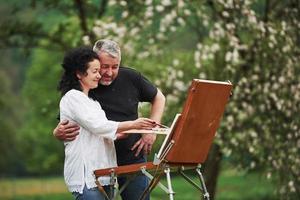 How it looks for you. Mature couple have leisure days and working on the paint together in the park photo