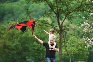 I wanna hold it. Running with red kite. Child sitting on the man's shoulders. Having fun photo