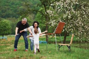 Give me embrace. Grandmother and grandfather have fun outdoors with granddaughter. Painting conception photo