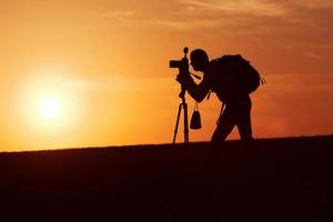 fotógrafo con equipos profesionales hace fotos. se encuentra en el campo iluminado por la luz del sol foto