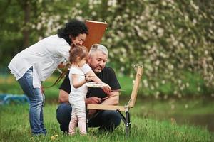 Working with different brushes. Grandmother and grandfather have fun outdoors with granddaughter. Painting conception photo