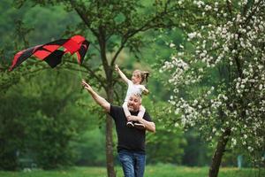 Active leisure. Running with red kite. Child sitting on the man's shoulders. Having fun photo