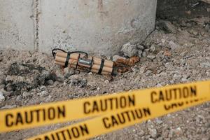 cerca del apoyo del puente. peligroso explosivo tirado en el suelo. cinta amarilla de precaución en el frente foto