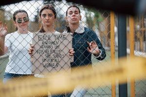 a través de la valla. grupo de mujeres feministas tienen protesta por sus derechos al aire libre foto
