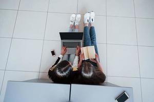 Smartphone, laptop and book. Top view of young people in casual clothes working in the modern office photo