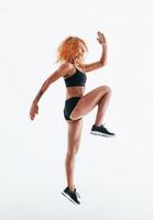 Having exercise. Redhead female bodybuilder is in the studio on white background photo
