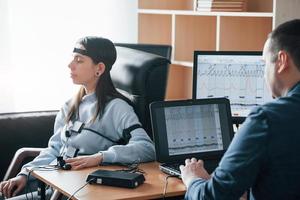 mujer tranquila la chica pasa el detector de mentiras en la oficina. haciendo preguntas. prueba de polígrafo foto